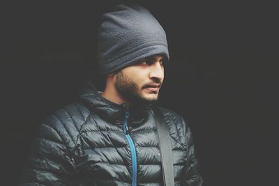 Young man wearing blue knit hat against black background