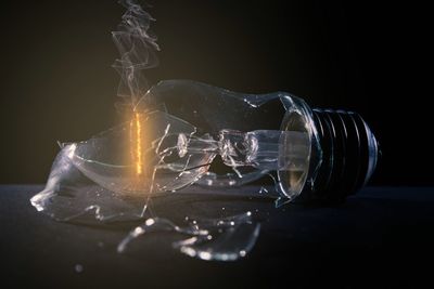 Close-up of broken light bulb over black background