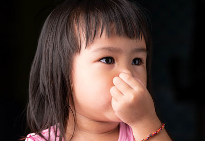 Close-up of cute girl covering nose with hand