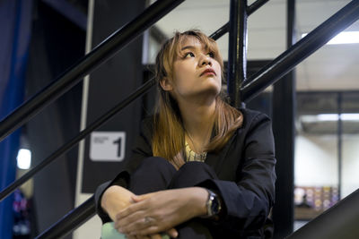 Low angle view of thoughtful businesswoman sitting against railing