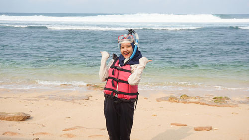Portrait of woman wearing snorkel standing on beach