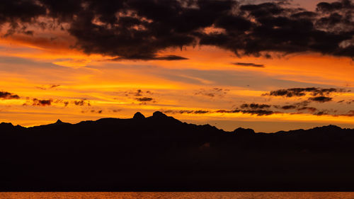 Scenic view of silhouette mountains against romantic sky at sunset