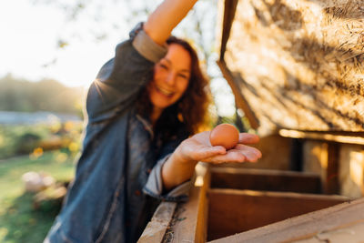 Country joy, woman with an egg in a country chicken coop.