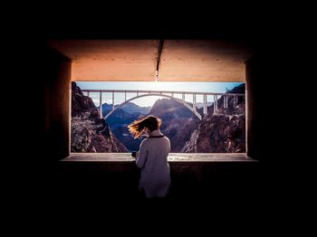 Rear view of woman standing in window