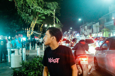 Young man looking at illuminated city at night