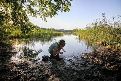 Man in lake by trees against sky