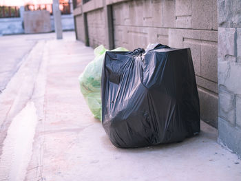 Garbage bin on sidewalk against wall