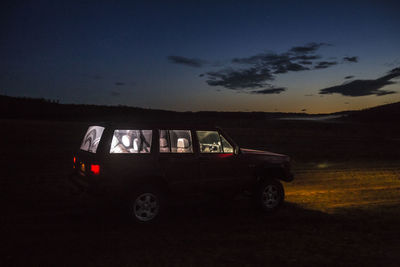 Car on field against sky at night