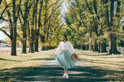 Portrait of woman standing on road amidst trees