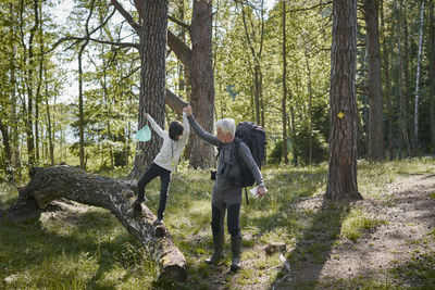 Full length of friends standing by trees in forest