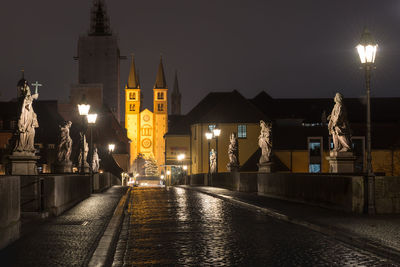 Illuminated street amidst buildings at night