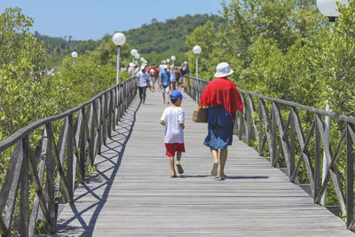 Rear view of woman walking on footbridge