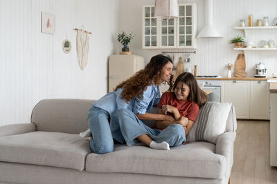 Young woman using phone while sitting on sofa at home