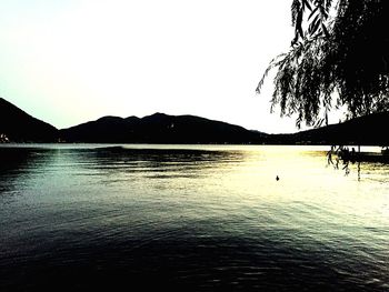 Scenic view of lake by silhouette mountains against clear sky