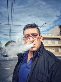 Portrait of man smoking against sky