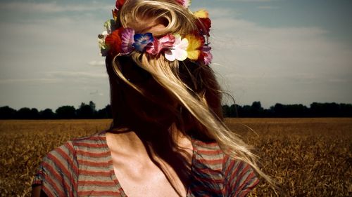 Woman wearing artificial flower crown while standing on field