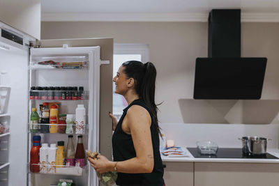 Woman standing in front of open fridge