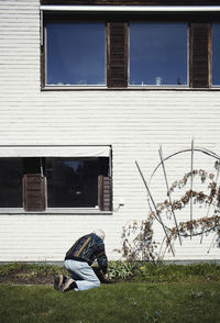 Woman sitting on field against building