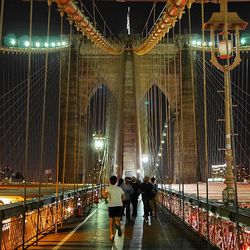 Woman walking on illuminated footbridge at night