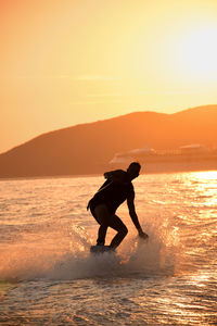 Side view of man wakeboarding against sky during sunset