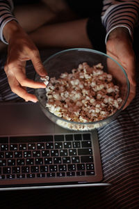 Cropped hand on woman holding bowl of pop corn