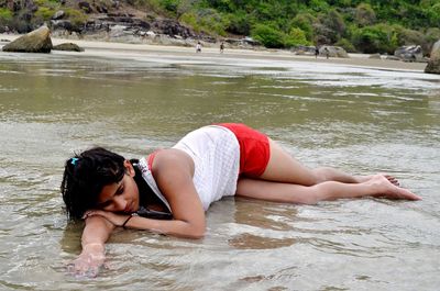 Full length of young woman lying in sea