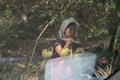 Woman sitting on field in forest