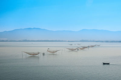 Boats sailing in sea against clear blue sky