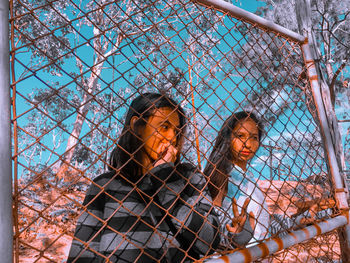 Portrait of young man seen through chainlink fence