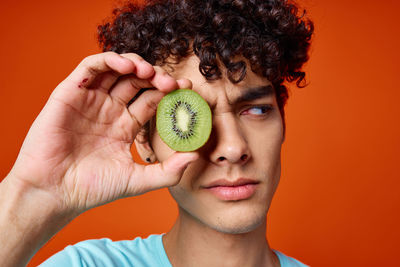 Portrait of man holding fruit against orange background