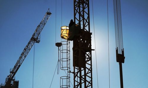 Low angle view of crane against clear blue sky