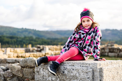 Portrait of girl sitting on seat at old ruins