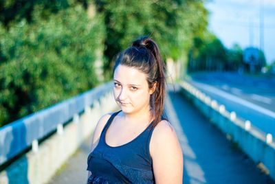 Portrait of woman standing on sidewalk in city