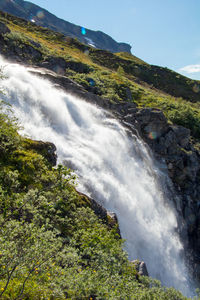 Scenic view of waterfall in forest against clear sky