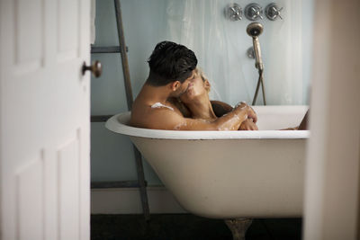 Young couple kissing in bathtub at home