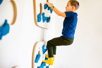 Side view of shirtless boy against wall