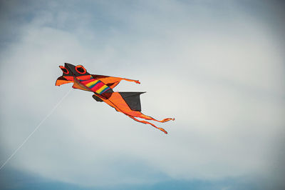 Close-up of colorful kite flying in sunny sky with clouds in the city center of ostia.