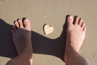 Low section of friends on sand at beach