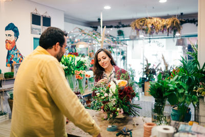 Rear view of man with woman holding bouquet at store