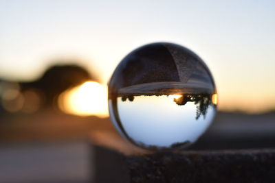 Close-up of crystal ball against sky during sunset