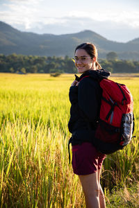 Side view portrait of woman standing at rice paddy against sky