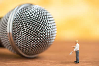 Close-up of male figurine and microphone on wooden table