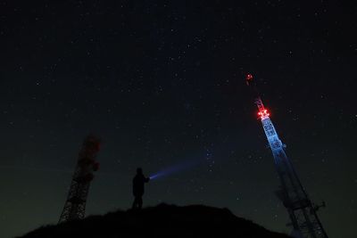 Low angle view of man standing on mountain at night