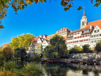 Buildings by river against blue sky