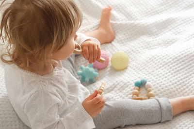 Cute baby girl playing tactile wooden and silicone toys. young child hand plays sensory massage ball