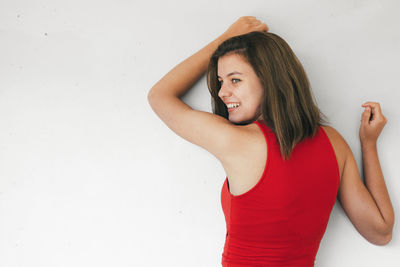 Portrait of young woman standing against white background