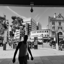 Rear view of man standing on street against buildings in city