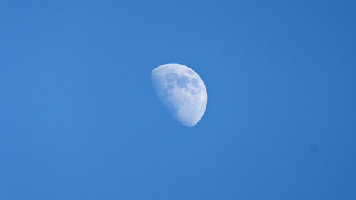 Low angle view of moon against blue sky