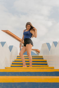 Low angle view of woman standing on staircase against sky