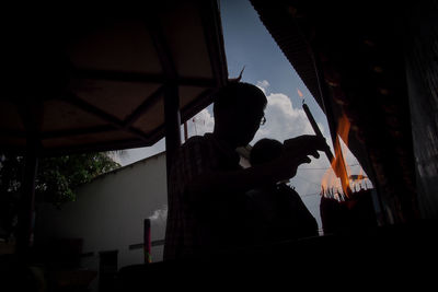 Low angle view of silhouette man holding window